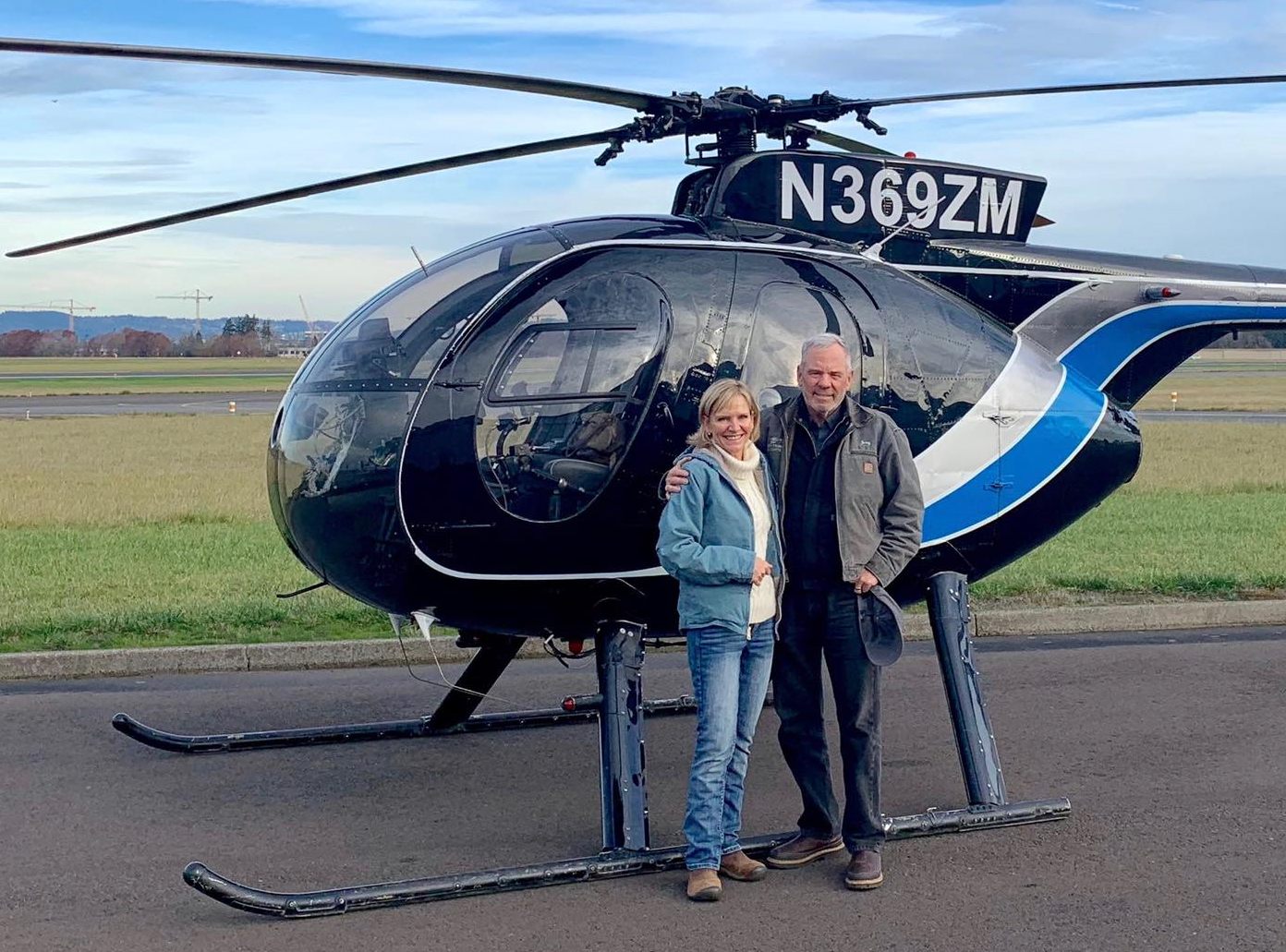 Jerry and Alison Trimble in front of an MD-500 helicopter at McMinnville Municipal Airport